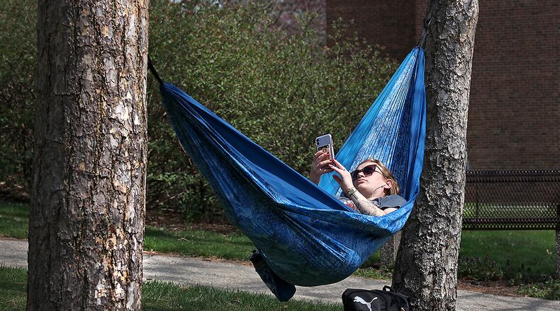 Corin Turkovich, a freshman at Wittenberg University from East Liverpool, Ohio, enjoys the warm air and sunshine earlier this week as she relaxes with some music in a hammock stretched between two trees on campus. BILL LACKEY/STAFF