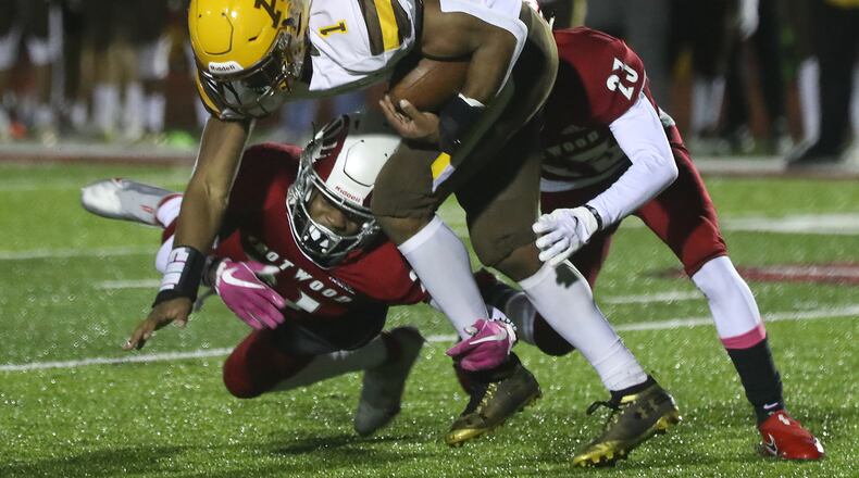 Alter's CJ Hicks is tackled by Trotwood's Dylan Heflin and Michael Smith. BILL LACKEY/STAFF
