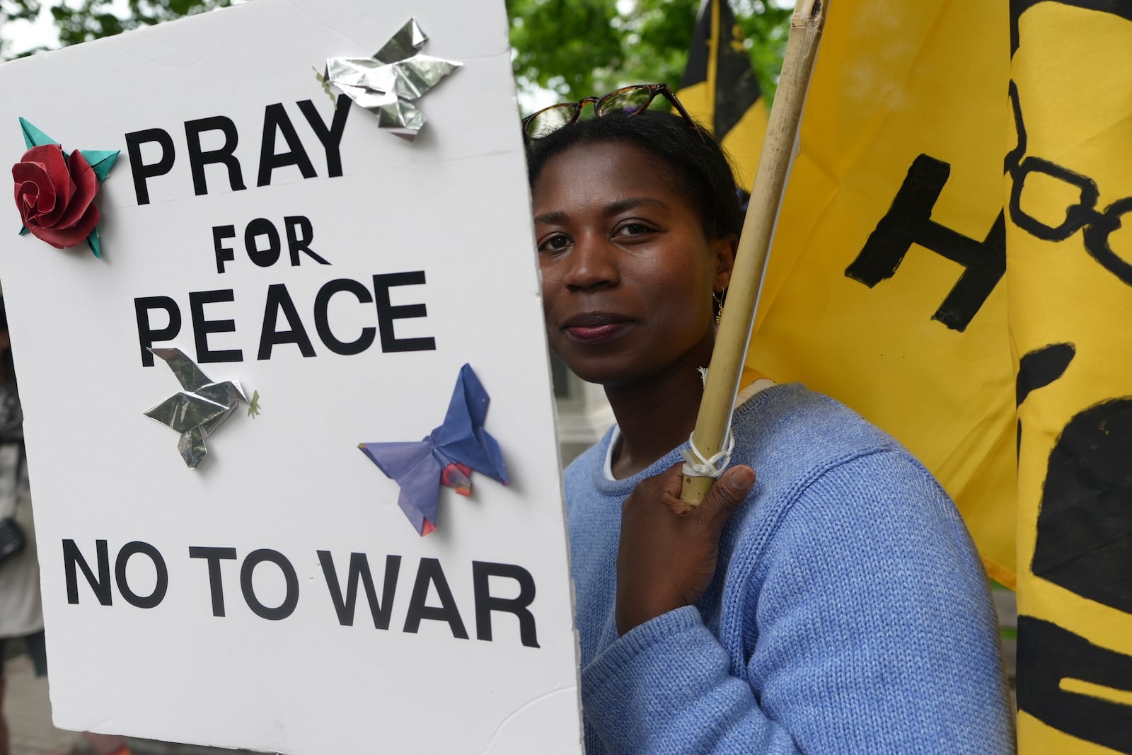 Casey Oware, a member of the Princeton Friends Meeting, holds a banner after meeting members of the Quaker March to Washington in Princeton, N.J., on Wednesday May 7, 2025. (AP Photo/Luis Andres Henao)