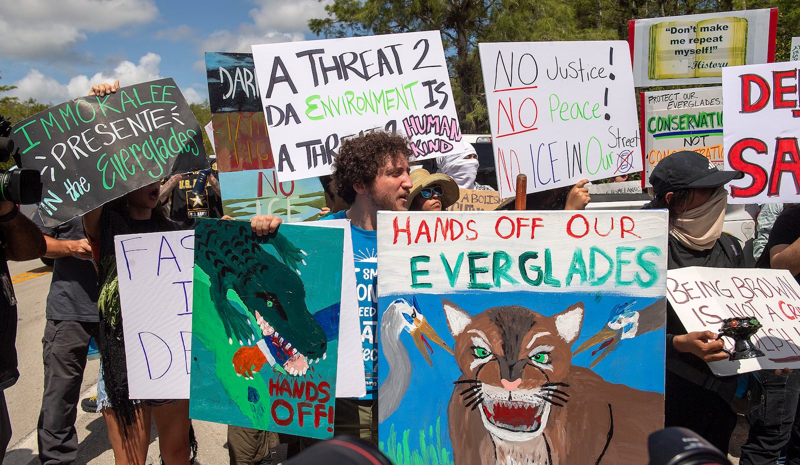 Protesters march outside the Dade-Collier Training and Transition Airport where President Donald Trump appeared, Tuesday, July 1, 2025, in Ochopee, Fla. (AP Photo/Michael Laughlin)