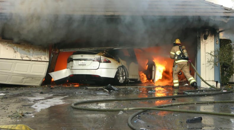 This undated photo provided by National Transportation Safety Board, The Orange County Fire Authority battles a fire on a burning vehicle inside a garage in Orange County, Calif. When firefighters removed the SUV from the garage to assess the fire , they identified the fuel source as the SUV’s high-voltage battery pack. U.S. safety investigators say electric vehicle fires pose risks to first responders, and manufacturers have inadequate guidelines to keep them safe. (Orange County Sheriff’s Department/National Transportation Safety Board via AP)