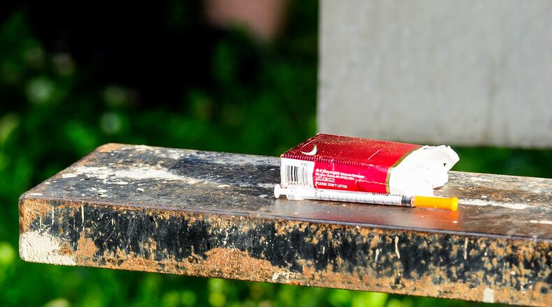 Middletown police officers secure property, including a needle, after they responded to a drug overdose behind the Midd-Town Carry Out on Central Avenue Monday, June 26, in Middletown. More people are dying from drug overdoses than any other cause in Butler County, according to new data from the coroner. NICK GRAHAM/STAFF
