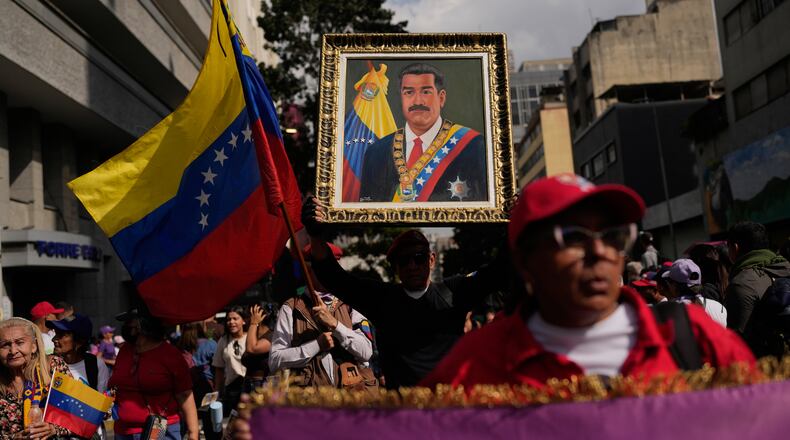 A government supporter holds an image of President Nicolas Maduro during a women's march to demand his return in Caracas, Venezuela, Tuesday, Jan. 6, 2026, three days after U.S. forces captured him and his wife. (AP Photo/Matias Delacroix)