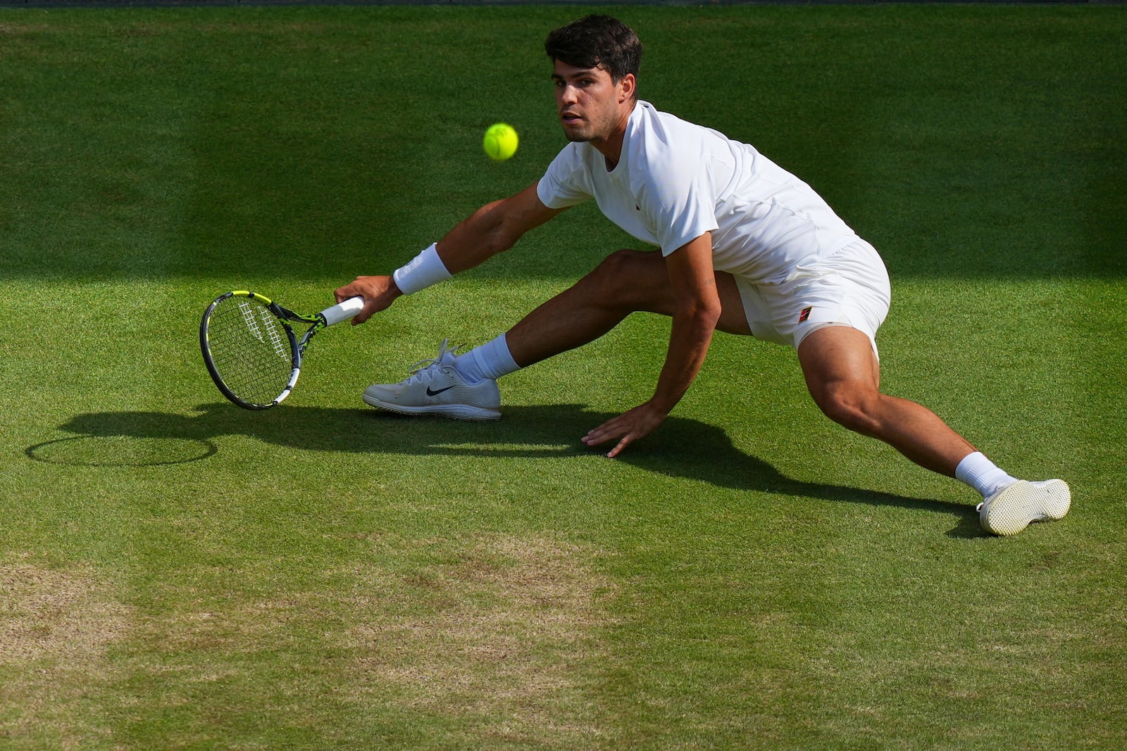 Carlos Alcaraz of Spain slips as he returns a shot by Italy's Jannik Sinner in the men's singles final at the Wimbledon Tennis Championships in London, Sunday, July 13, 2025. (AP Photo/Joanna Chan)