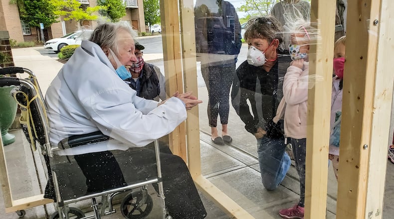 The family of Virginia “Ginny” Meyer, 95, was finally able to see her up closed thanks to a clear, protective box the family built to be placed outside Barrington of West Chester senior living facility Wednesday, May 13, 2020. Meyer’s children, grandchildren and great-grandchildren greeted her as she came out the door to see them up close for the first time in over two months due to the coronavirus pandemic. If they wanted to see her before they had to see her from her third floor balcony. NICK GRAHAM / STAFF
