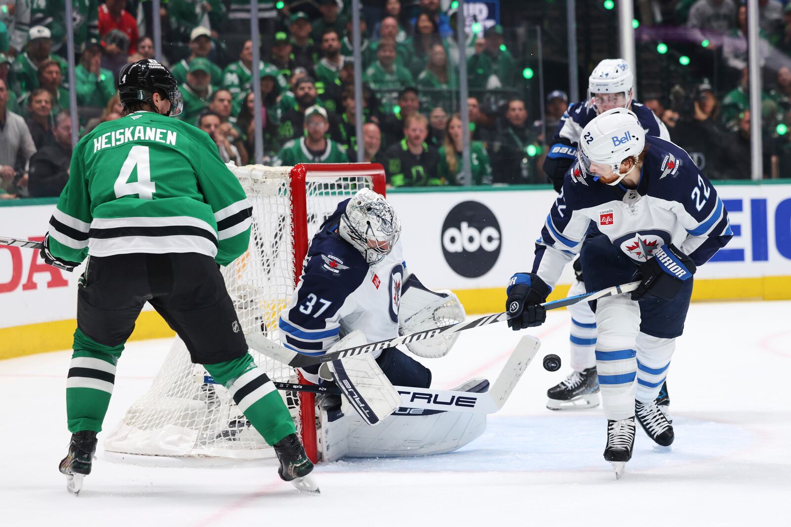 Winnipeg Jets goaltender Connor Hellebuyck (37) blocks a shot as center Mason Appleton (22) helps against pressure from Dallas Stars defenseman Miro Heiskanen (4) in the first period of Game 6 of a second-round NHL hockey playoff series in Dallas, Saturday, May 17, 2025. (AP Photo/Gareth Patterson)
