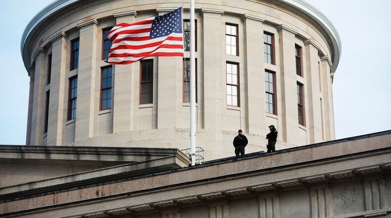 FILE - In this Jan. 13, 2021 file photo, fwo Ohio State Highway Patrol troopers look out from the Ohio Statehouse roof in Columbus.  Republican lawmakers in Ohio on Thursday, June 24, have moved to approve a bill banning transgender girls from participating in female sports teams in high school or college. The proposal, titled the Save Women’s Sports Act, would require schools and higher education institutions in the state to designate “separate single-sex teams and sports for each sex.”   (Doral Chenoweth/The Columbus Dispatch via AP)