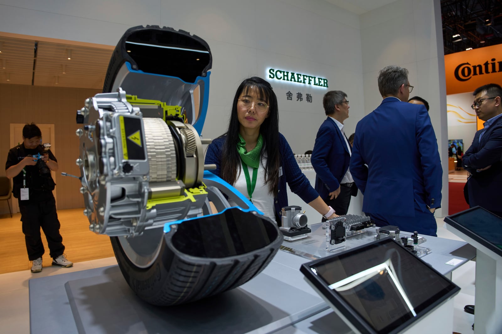 A worker stands near a cut out of a wheel at the booth for Schaeffler at the Shanghai auto show on Thursday, April 24, 2025. (AP Photo/Ng Han Guan)