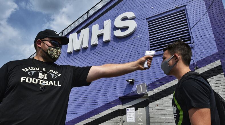 Offensive line coach Matt Money checks temperature of sophomore Nicholas Cox before football practice Tuesday, August 25, 2020 at Barnitz Stadium in Middletown. NICK GRAHAM / STAFF