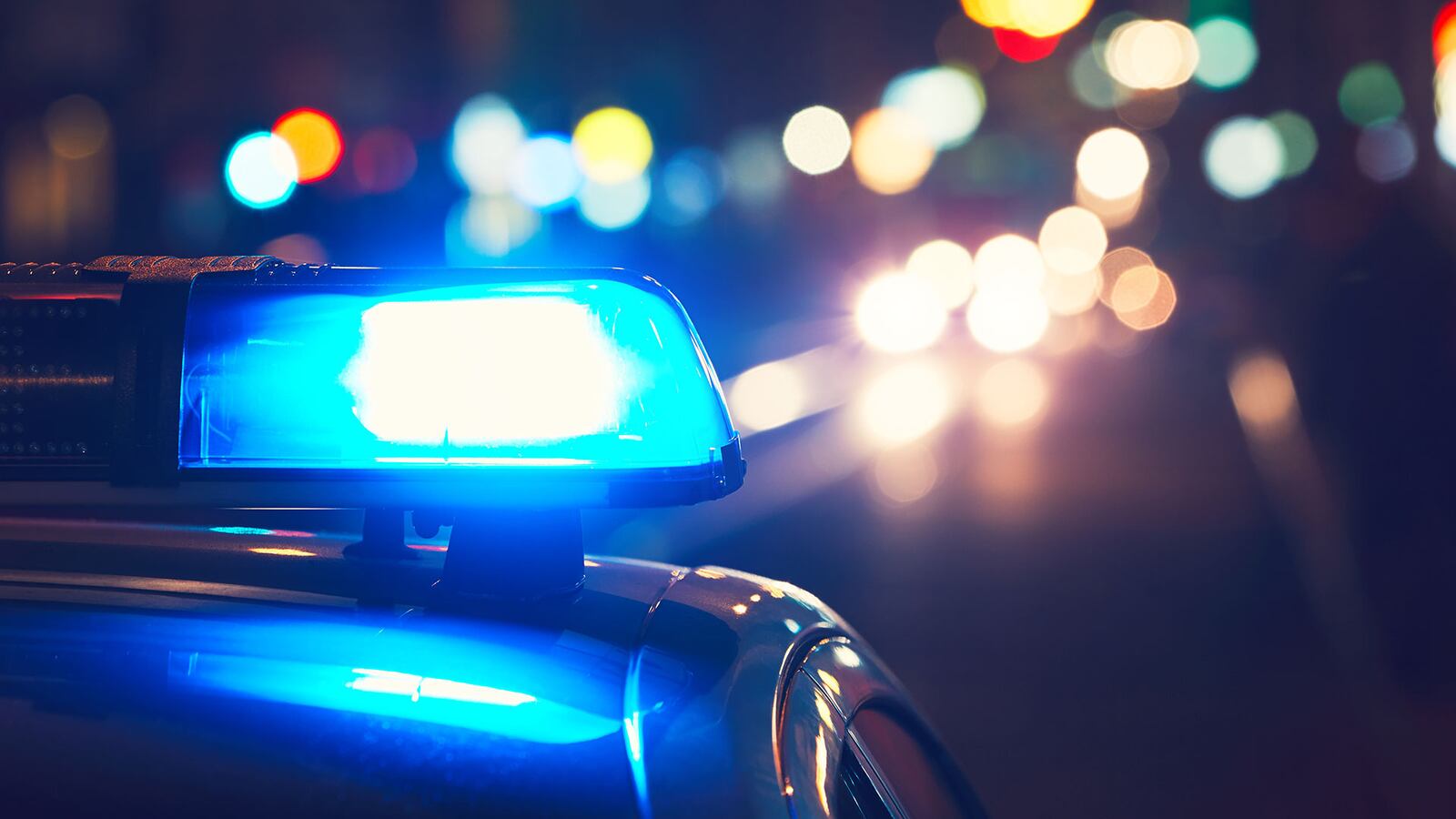 Danger on the road. Blue flasher on the police car at night.