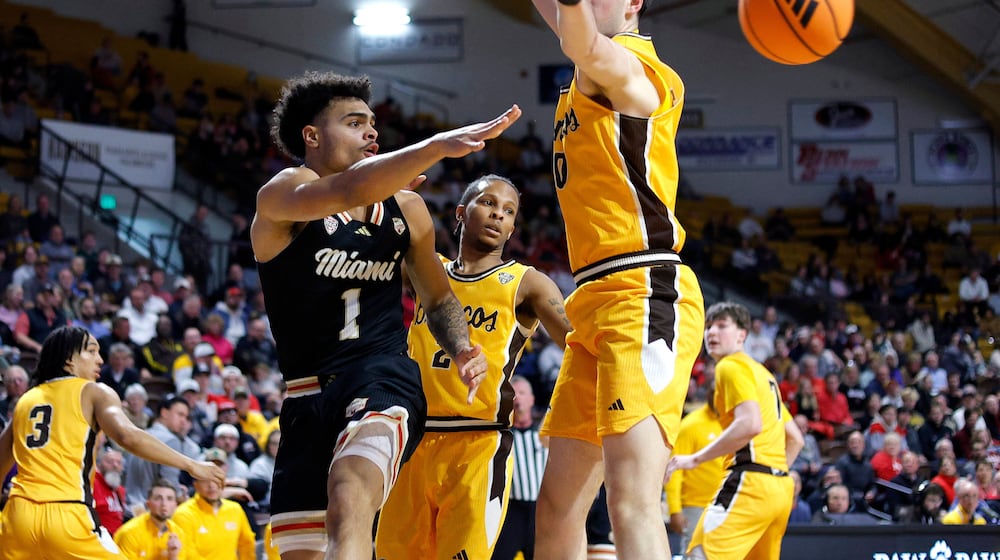Miami (Ohio) guard Trey Perry (1) dishes off the ball against Western Michigan forward Max Burton during the first half of an NCAA college basketball game, Friday, Feb. 27, 2026, in Kalamazoo, Mich. (AP Photo/Al Goldis)
