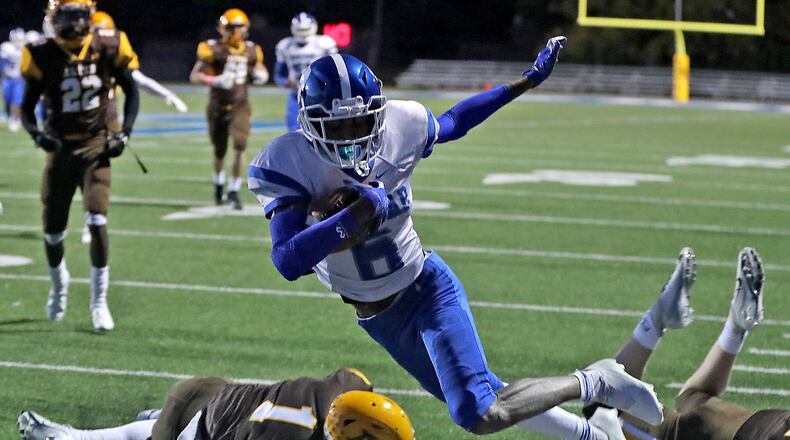 Dunbar's Shaun Huffman dives into the end zone after avoiding tackles from two Alter defenders Friday. BILL LACKEY/STAFF