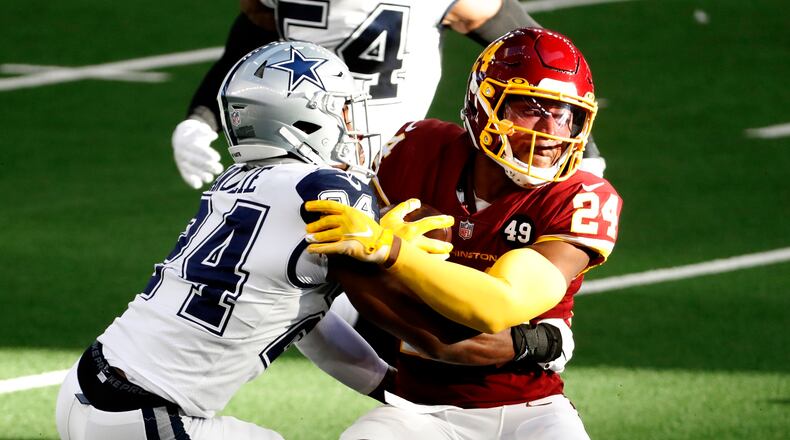 Washington Football Team running back Antonio Gibson (24) is stopped on a carry by Dallas Cowboys cornerback Chidobe Awuzie, left, in the first half of an NFL football game in Arlington, Texas, Thursday, Nov. 26, 2020. (AP Photo/Roger Steinman)