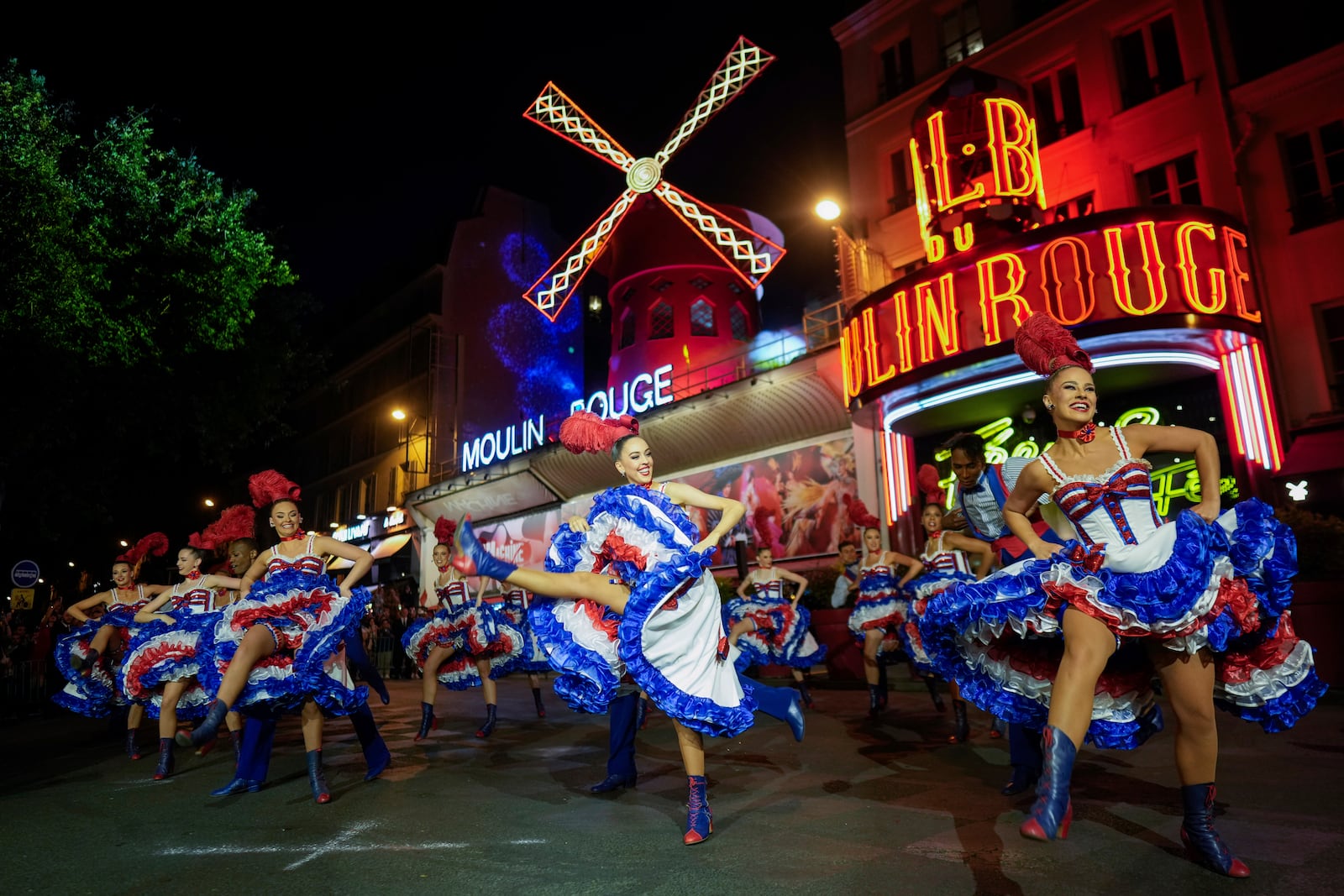FILE - Dancers perform in front of the Moulin Rouge cabaret during the inauguration of the theatre's windmill in Paris, Friday, July 5, 2024. (AP Photo/Thibault Camus, File)