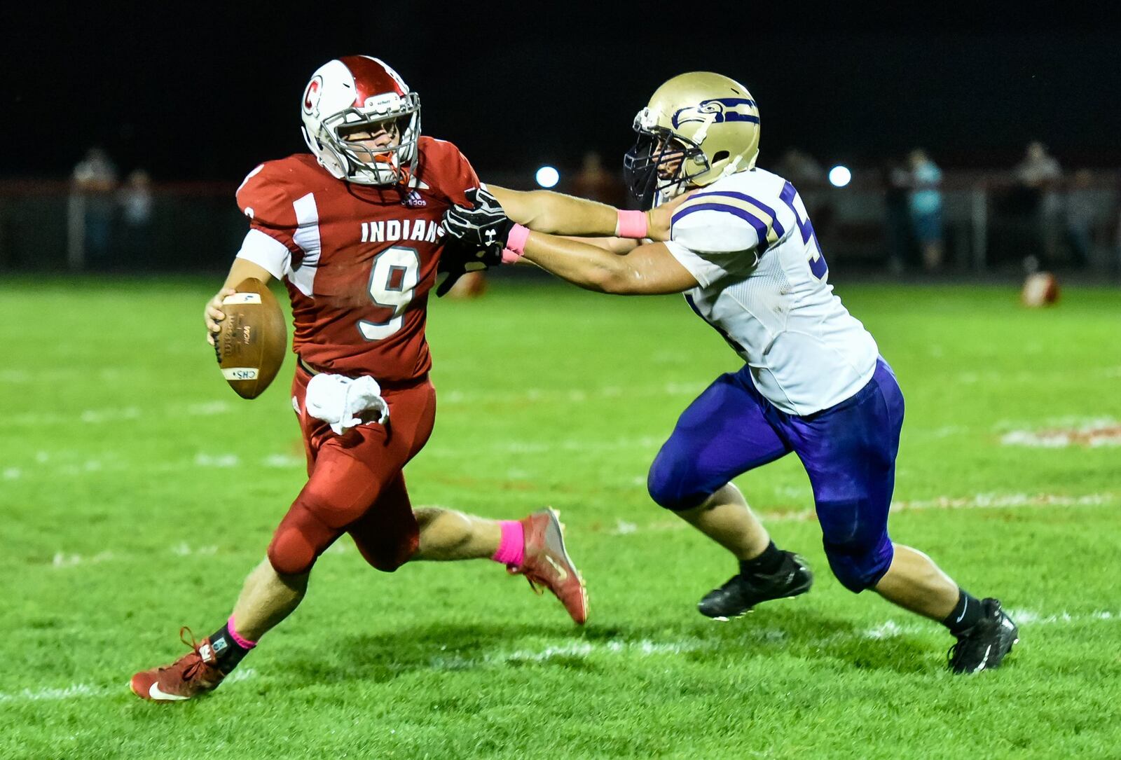 Carlisle quarterback Jake Moore tries to elude Eaton’s Breven Perry (54) during Thursday night’s game at Laughlin Field in Carlisle. NICK GRAHAM/STAFF