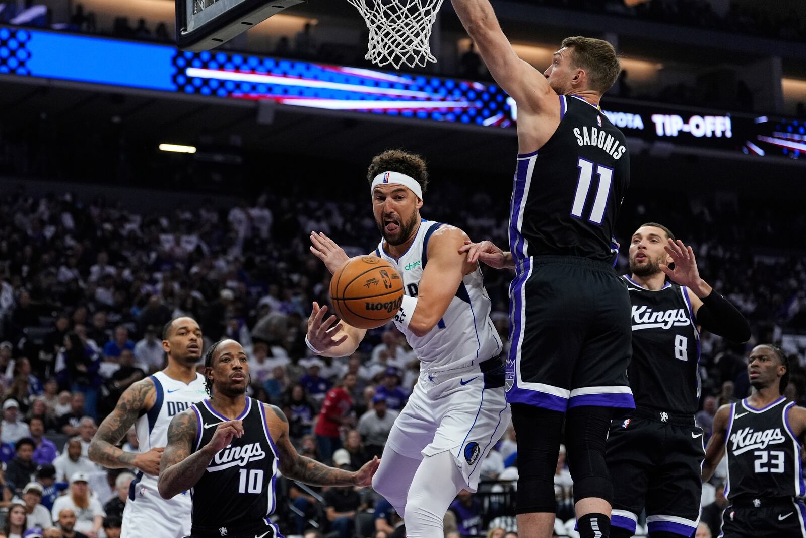 Dallas Mavericks guard Klay Thompson, center, passes the ball while defended by Sacramento Kings center Domantas Sabonis (11) during the first half of an NBA play-in tournament basketball game Wednesday, April 16, 2025, in Sacramento, Calif. (AP Photo/Godofredo A. Vásquez)