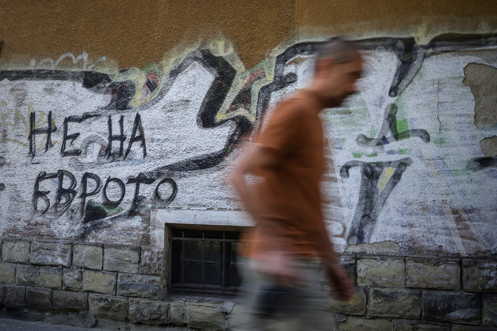 A man passes by graffiti sign reading 'No to Euro' in Sofia, Bulgaria, Monday, June 2, 2025. (AP Photo/Valentina Petrova)