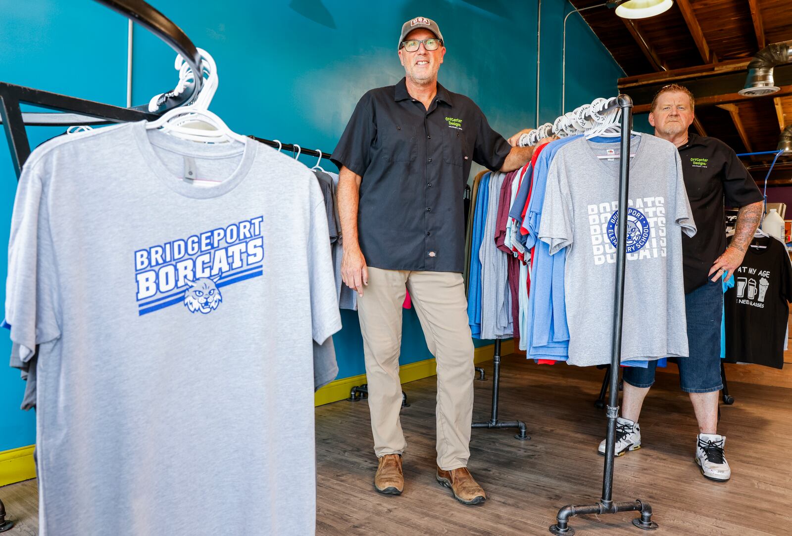 Owner John Stanley, left, and Tyrone Davidson stand in OffCenter Designs on Main Street in Hamilton. The shop offers custom screen printing and embroidery services for clothing and more. NICK GRAHAM/STAFF