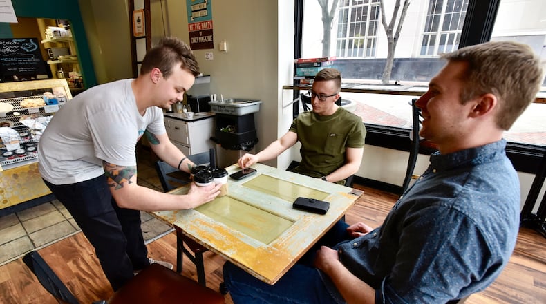 Evan Vossman, left, brings Brad Paynter, middle, and John Monnig their coffee at True West Coffee Downtown on High Street Friday, April 5, 2019 in Hamilton. NICK GRAHAM/STAFF