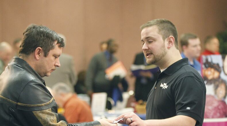 Air Force veteran Bill Lamar, left, takes a card from Invertix senior technical recruiter Nathan Cargle at a job fair in 2014 hosted by the Military Veterans Resource Center at the Hope Hotel and Conference Center. TY GREENLEES / STAFF FILE PHOTO
