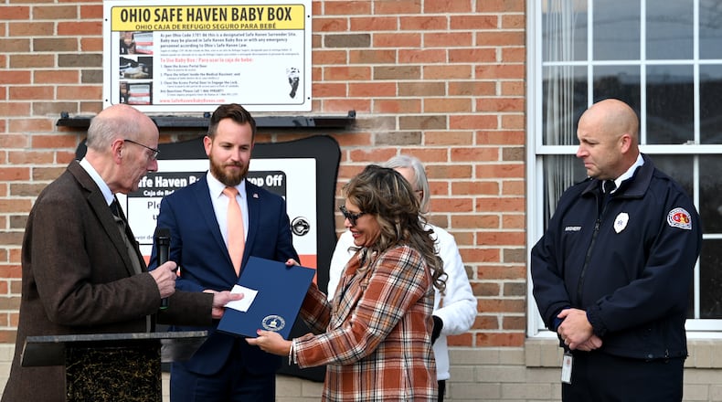 Monica Kelsey, of Safe Haven Baby Boxes, the organization named for Ohio's Safe Haven lawn, receives a proclamation on Tuesday afternoon, Nov. 11, 2025, from Hamilton Mayor Pat Moeller on the organization's 20th baby box in Ohio. Hamilton dedicated Butler County's first Safe Haven Baby Box at the Fire Station 22 on Pershing Avenue. The box is designed to allow mothers to anonymously place a newborn baby 30 days or younger in the incubator. Fire personnel are notified through a silent alarm. Mothers can still surrender a baby at any hospital, fire department or police station under Ohio's Safe Haven law. MICHAEL D. PITMAN/STAFF