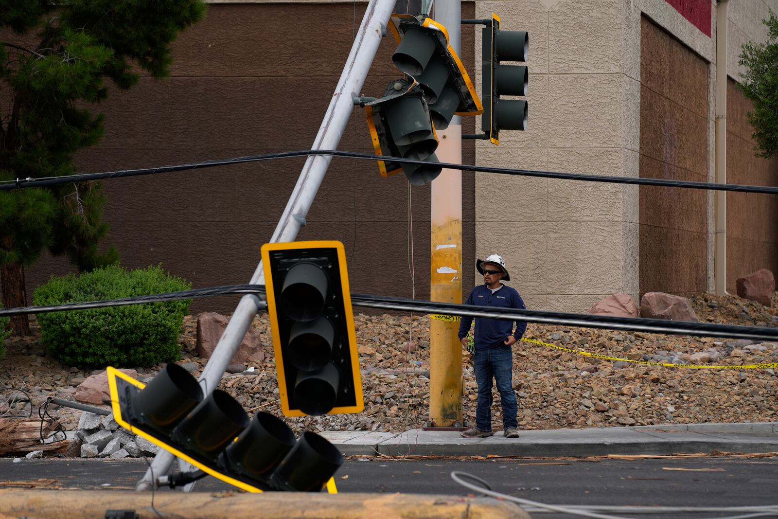 A worker stands beside traffic lights damaged in a storm Wednesday, July 2, 2025, in Las Vegas. (AP Photo/John Locher)