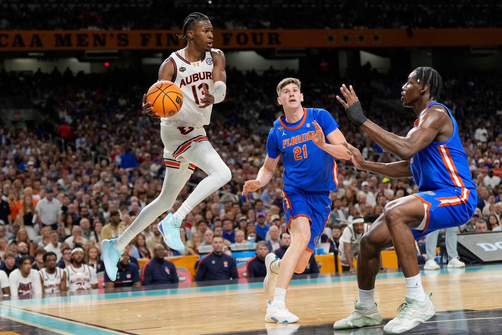Auburn's Miles Kelly (13) looks to pass the ball as Florida's Alex Condon (21) and Rueben Chinyelu defend during the second half in the national semifinals at the Final Four of the NCAA college basketball tournament, Saturday, April 5, 2025, in San Antonio. (AP Photo/Eric Gay)