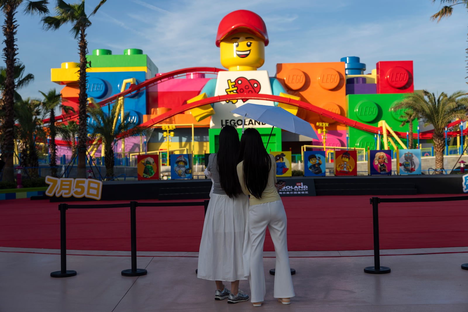 Women look at a giant Lego character at Legoland Shanghai a day before it opens to the public in Shanghai, China, Friday, July 4, 2025. (AP Photo/Ng Han Guan)