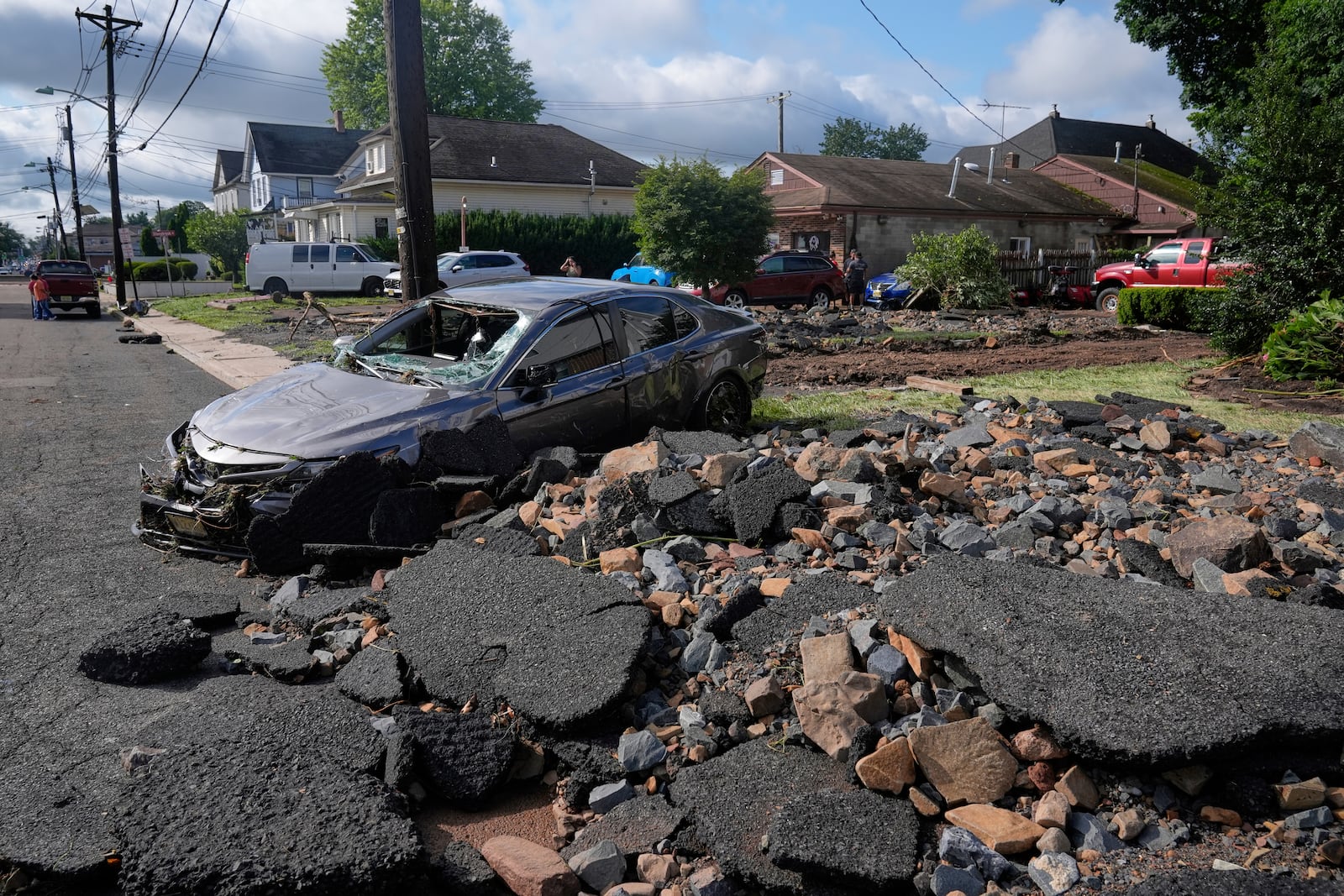 Debris, rubble and a damaged car lie on a street after flooding from rains in the area in North Plainfield, N.J., Tuesday, July 15, 2025. (AP Photo/Seth Wenig)