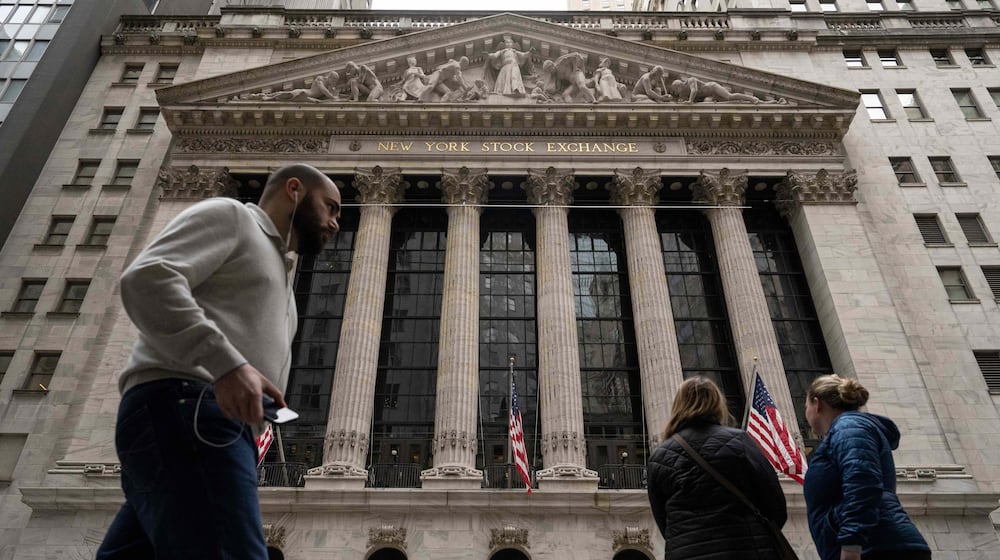 People walk past the New York Stock Exchange, Friday, March 27, 2026, in New York. (AP Photo/Yuki Iwamura)