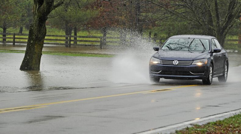 A car splashes through water from a flooded yard covering part of Millikin Road between Yankee and Cincinnati Dayton roads in 2011 in Liberty Twp. For at least 60 years flood waters have wrecked havoc along Millikin Road between Cincinnati Dayton and Yankee roads, pushing way past the road limits, deluging lawns and basements and stalling cars trying to get through. This week the Butler County commissioners signed off on a $980,279 contract to fix the problem. NICK GRAHAM/STAFF