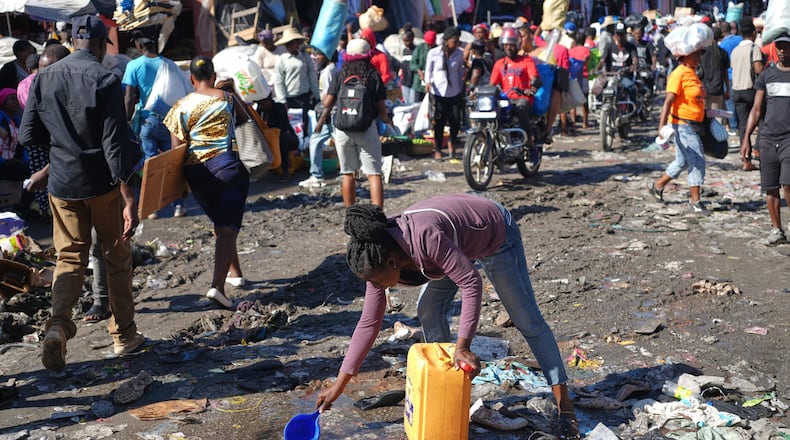 A woman collects water from a puddle in the Petion-Ville neighborhood of Port-au-Prince, Haiti, Wednesday, Feb. 11, 2026. (AP Photo/Odelyn Joseph)
