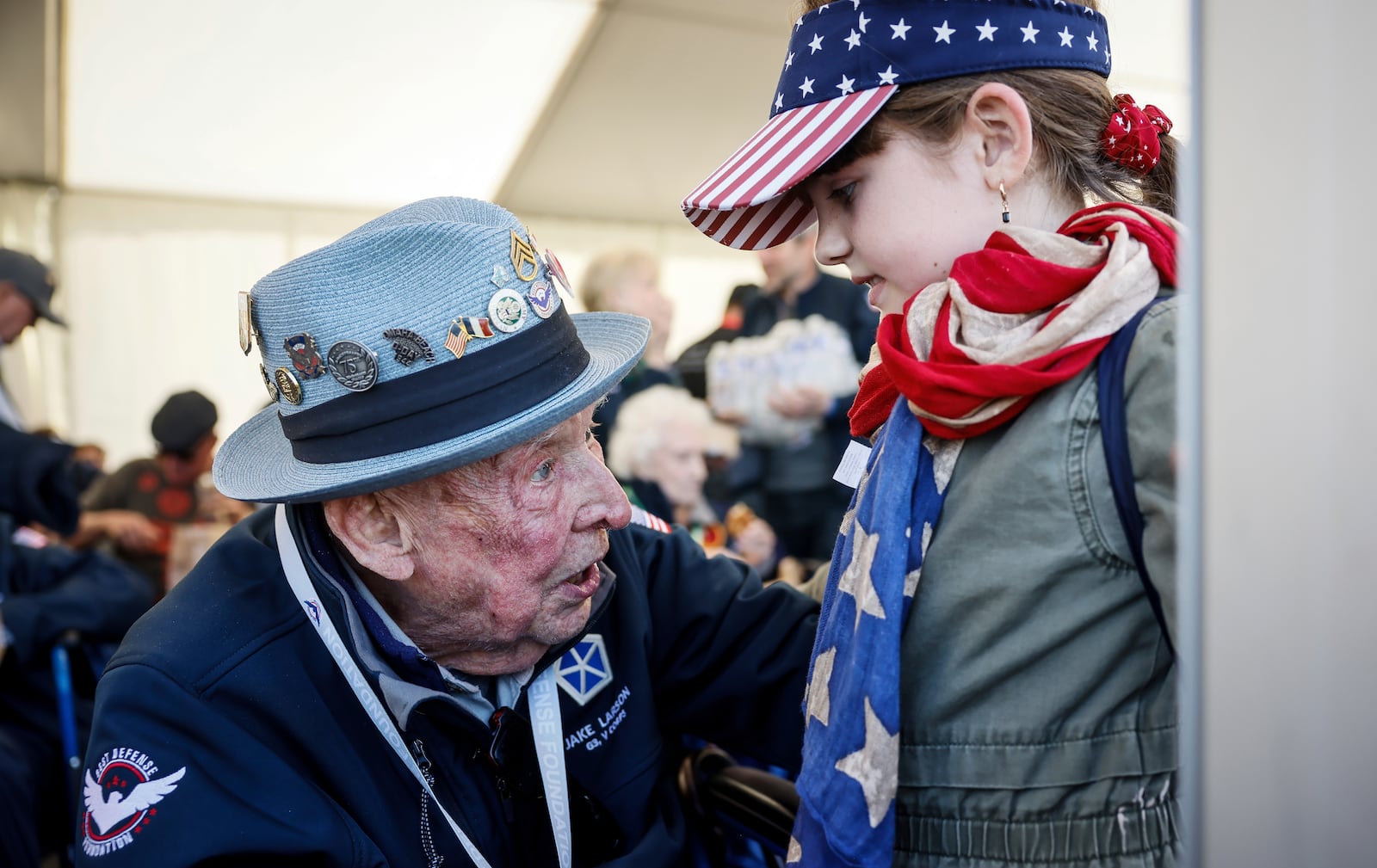 FILE - U.S. veteran SSgt. Jake M. Larson talks to a girl who wears an American flag around her neck during a gathering in preparation of the 79th D-Day anniversary in La Fiere, Normandy, France, June 4, 2023. (AP Photo/Thomas Padilla, file)