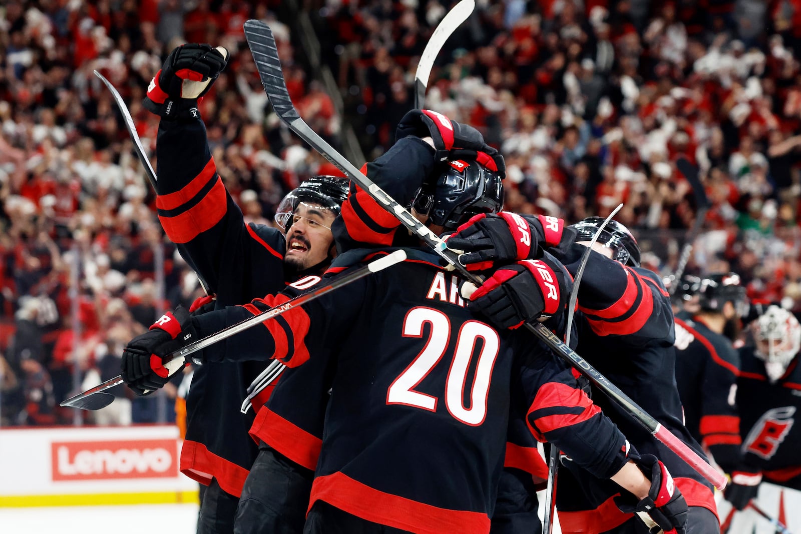 Carolina Hurricanes' Seth Jarvis, left, salutes the crowd from the celebration of Sebastian Aho's game-winning goal during the second overtime period of Game 5 of an NHL hockey Stanley Cup first-round playoff series against the New Jersey Devils in Raleigh, N.C., Tuesday, April 29, 2025. (AP Photo/Karl DeBlaker)