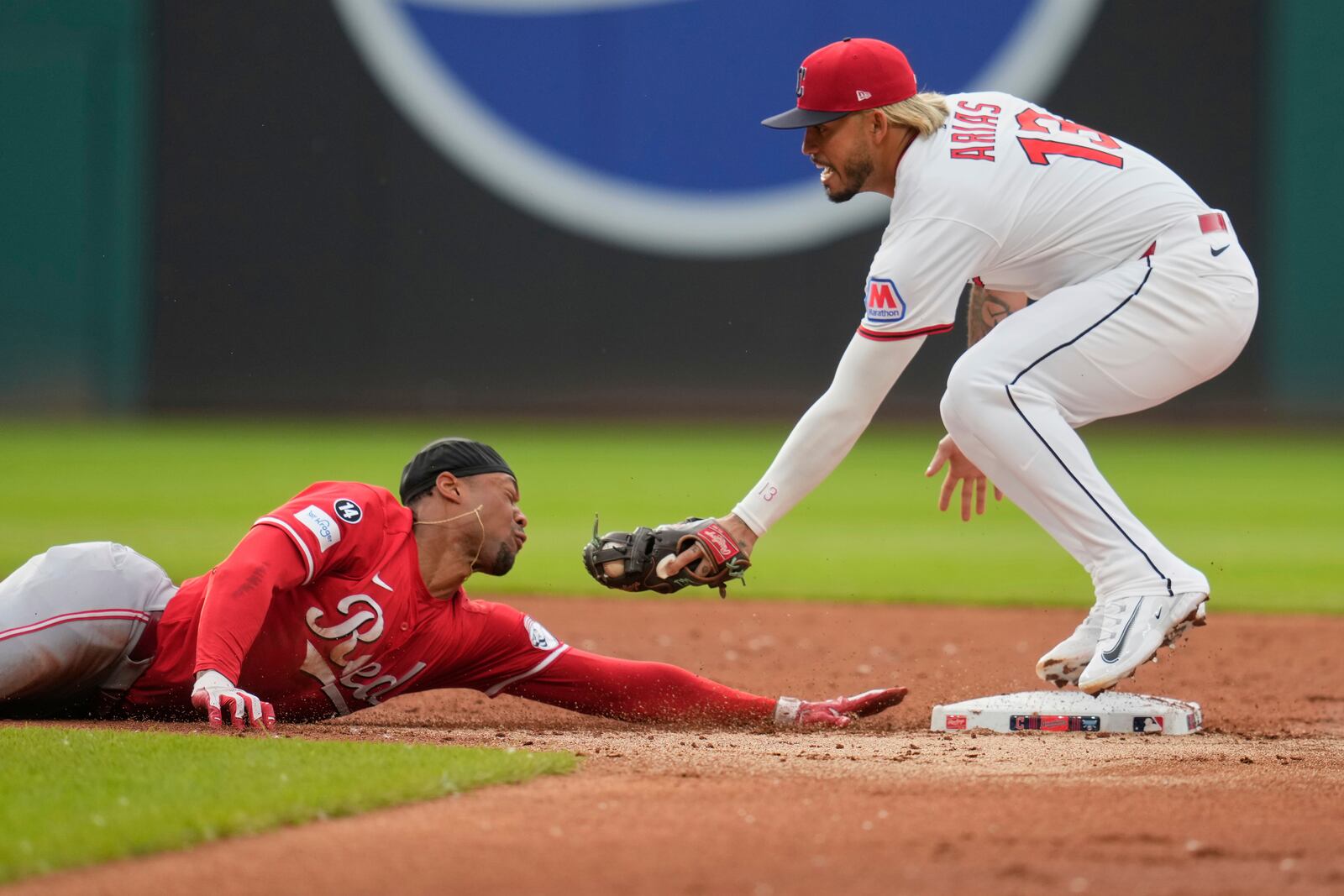 Cincinnati Reds' Will Benson, left, slides safely back to second base as Cleveland Guardians shortstop Gabriel Arias attempts the tag on a pick off attempt in the second inning of a baseball game in Cleveland, Monday, June 9, 2025. (AP Photo/Sue Ogrocki)
