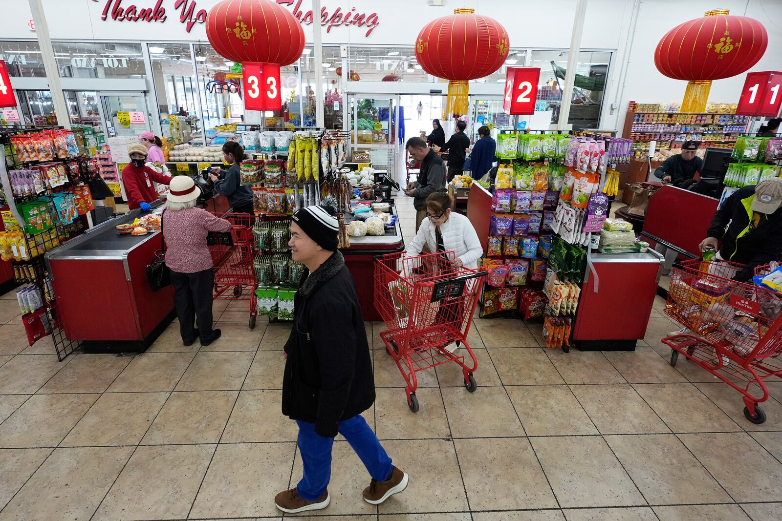 Chan 'Bill' Vuu, owner of Hiep Thai grocery store, walks past cashiers and customers at his family's store in Garland, Texas, Monday, April 7, 2025. (AP Photo/LM Otero)