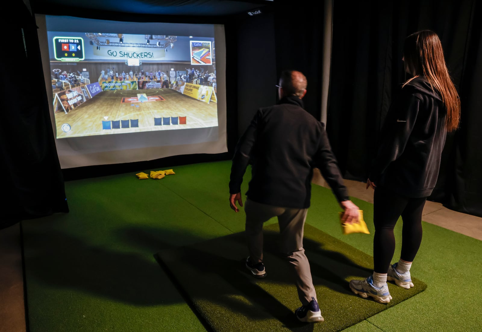 Jim Burns, left, and Mikahla Coulter play cornhole at Inside 18 golf and sports simulator Thursday, Jan. 15, 2026 at Spooky Nook Sports Champion Mill in Hamilton.  The new indoor sports simulator facility is mostly used for golf, but it also features baseball, soccer, football and other sports. NICK GRAHAM/STAFF