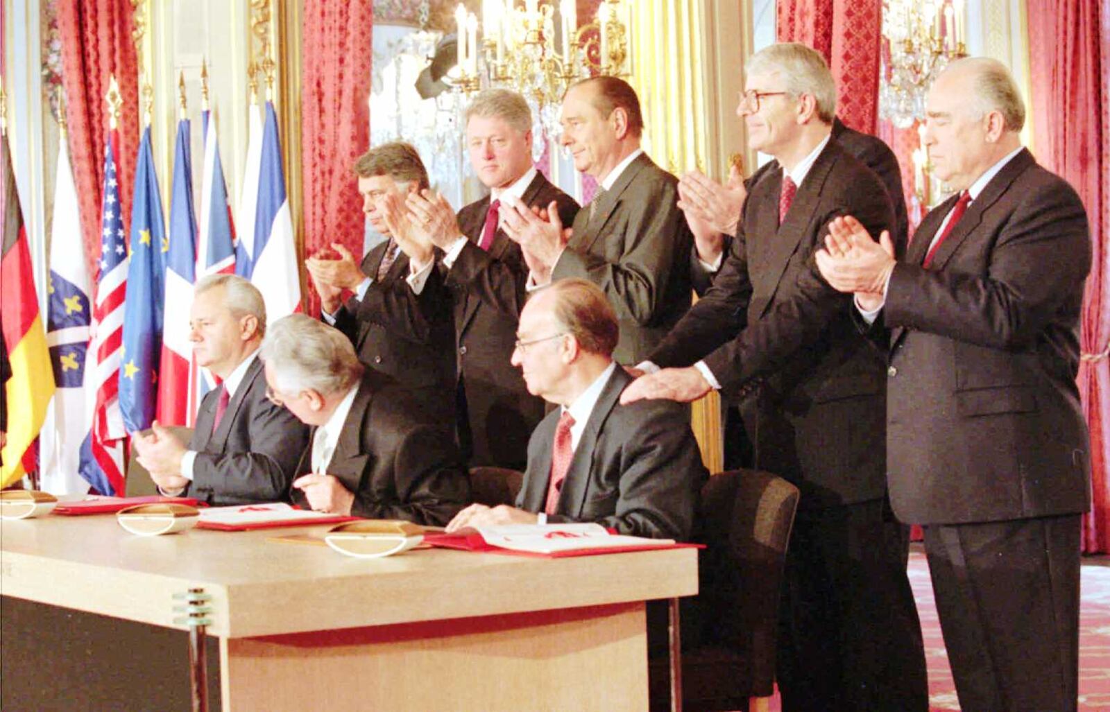 World leaders, from left, standing, Spanish Premier Felipe Gonzales, President Clinton, French President Jacques Chirac, German Chancellor Helmut Kohl, (hidden), British Premier John Major and Russian Premier Viktor Chernomyrdin, applaud the signing of the treaty to bring peace in the Balkans at the Elysee Palace, Paris, Thursday Dec. 14, 1995. Seated from left signing are Balkan leaders President Slobodan Milosevic, Serbia; Franjo Tudjman, Croatia and Alija Izetbegovic of Bosnia. (AP Photo/Jerome Delay,pool)