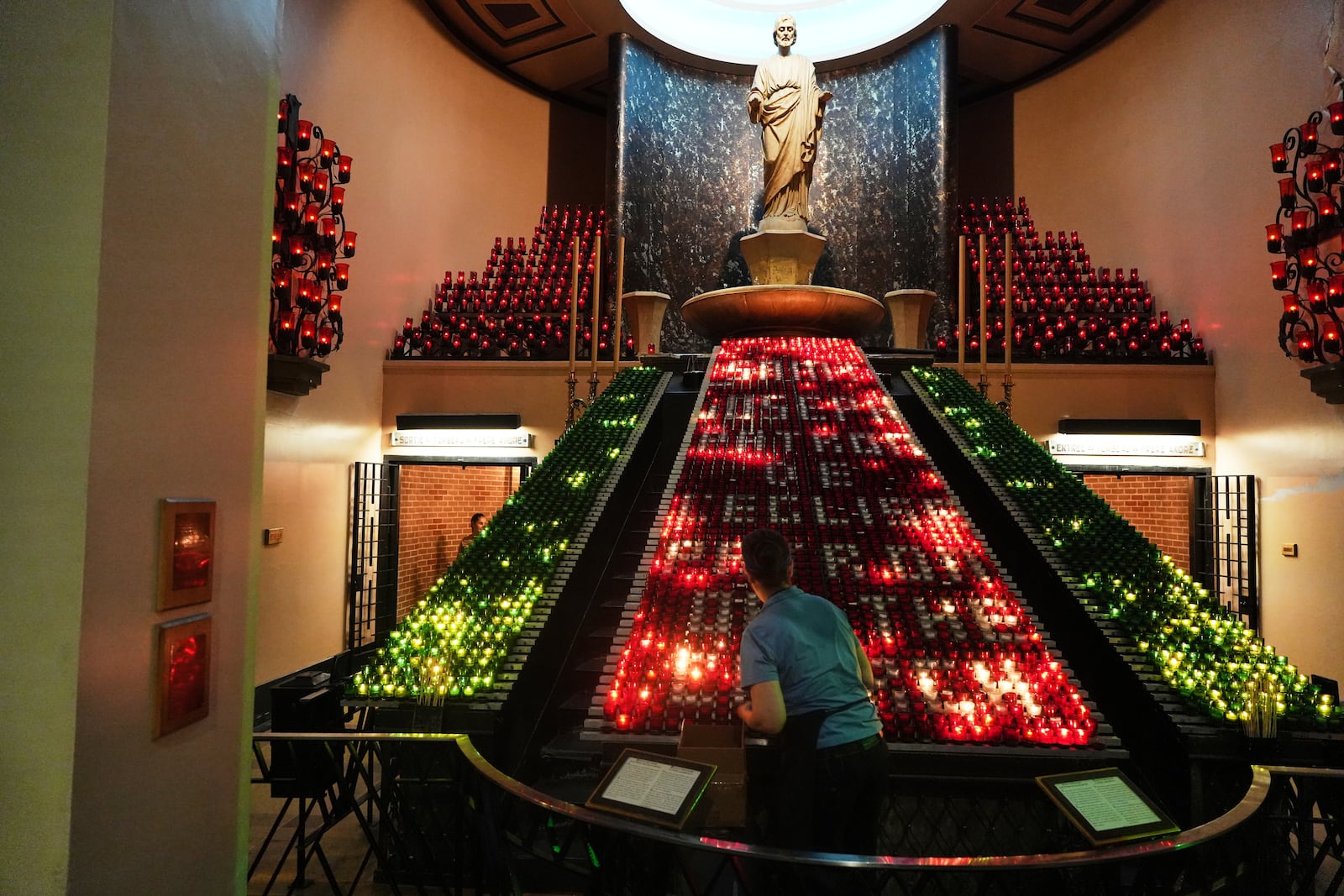 A worker arranges candles inside the Votive Chapel at the national shrine of Saint Joseph's Oratory of Mount Royal, in Montreal, Saturday, June 28, 2025. (AP Photo/Luis Andres Henao)