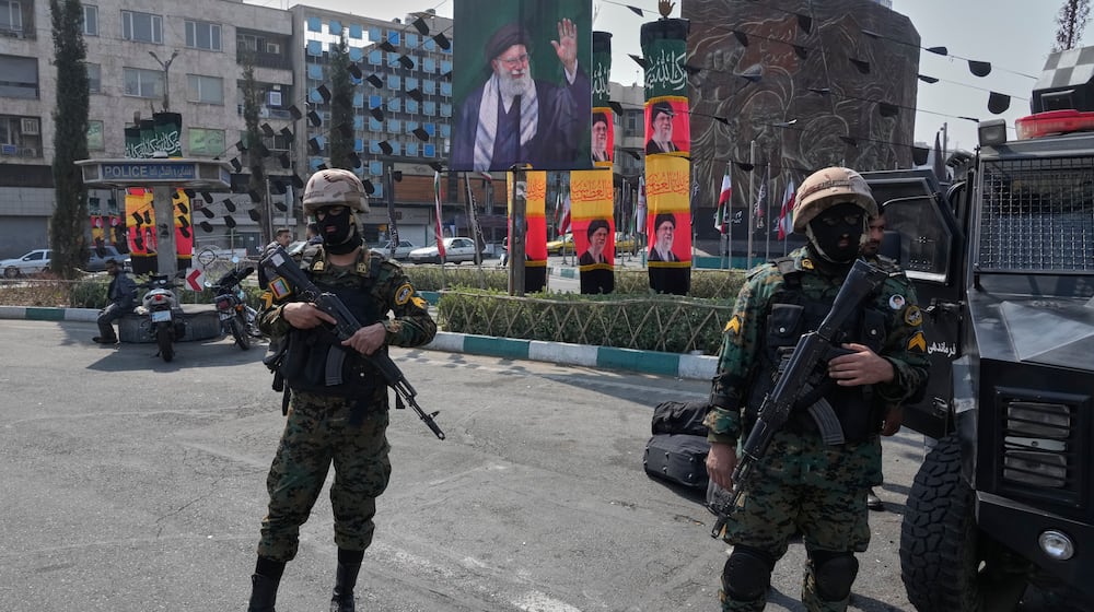 Policemen stand guard next to the banners showing portraits of the late Iranian Supreme Leader Ayatollah Ali Khamenei at the Enqelab-e-Eslami, or Islamic Revolution, square in downtown Tehran, Iran, Saturday, March 14, 2026. (AP Photo/Vahid Salemi)