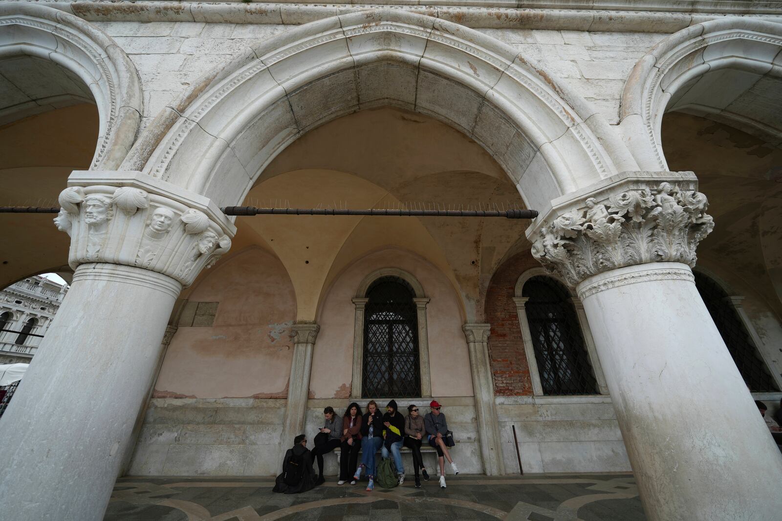 Tourists take a break in San Marco square in Venice, Italy, Friday, April 18, 2025, Venice on Friday launches for a second year a pilot program to charge day-trippers an entrance fee. (AP Photo/Antonio Calanni)