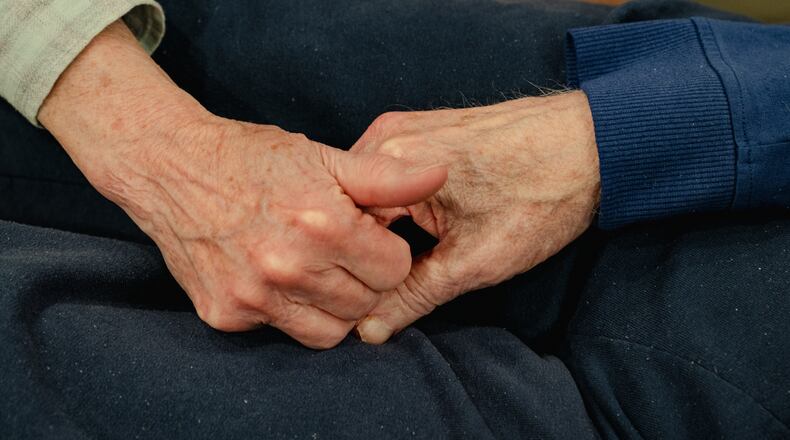 AP File - Dottye Burt holds the hand of her husband Stan Markowitz, who was battling Parkinson’s disease, at Keswick Multi-Care Center in Baltimore on Oct. 25, 2022. Nursing homes in the Dayton region are facing challenges with staffing, leading them to relying on health care staffing agencies, which are not regulated. (Shuran Huang/The New York Times)