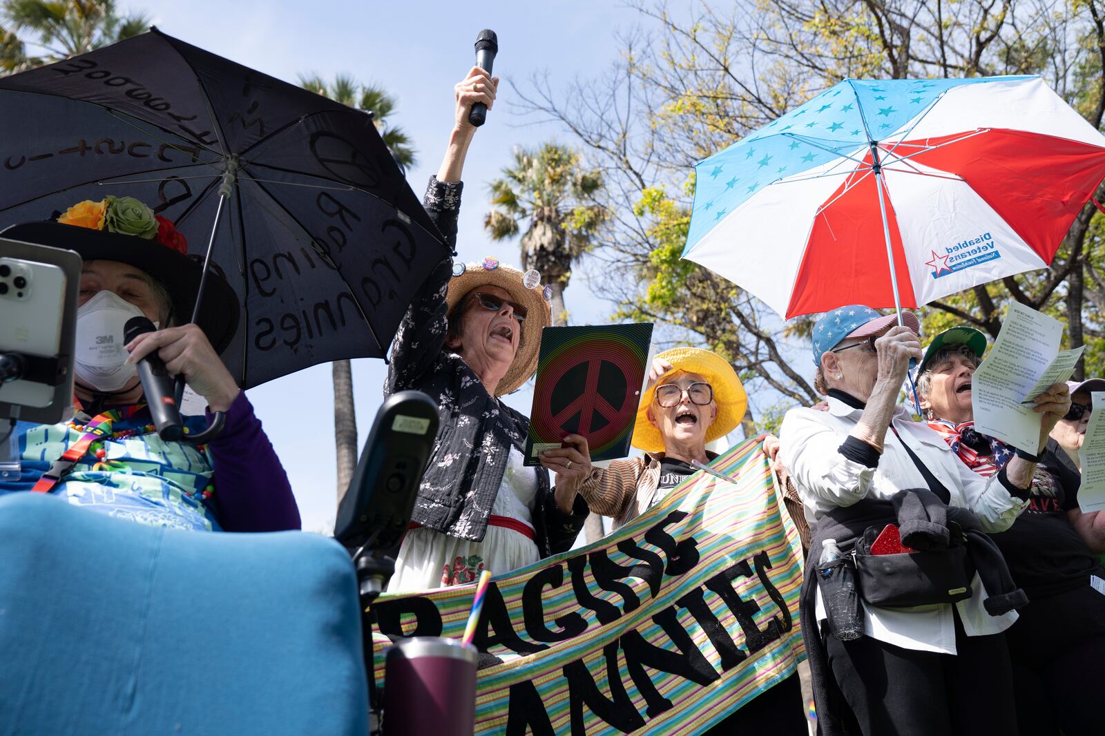 Demonstrators sing a song of protest at a rally against President Donald Trump and Tesla CEO Elon Musk in San Jose, Calif., as part of a national day of action on Saturday, April 5, 2025. (AP Photo/Emily Steinberger)