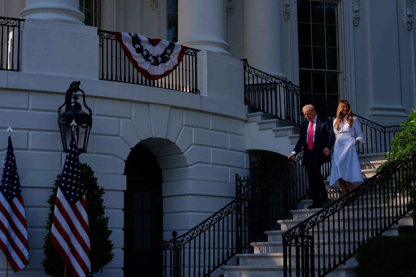 President Donald Trump and first lady Melania Trump walk down the steps from the Blue Room Balcony to sign his signature bill of tax breaks and spending cuts at the White House, Friday, July 4, 2025, in Washington. (AP Photo/Julia Demaree Nikhinson)