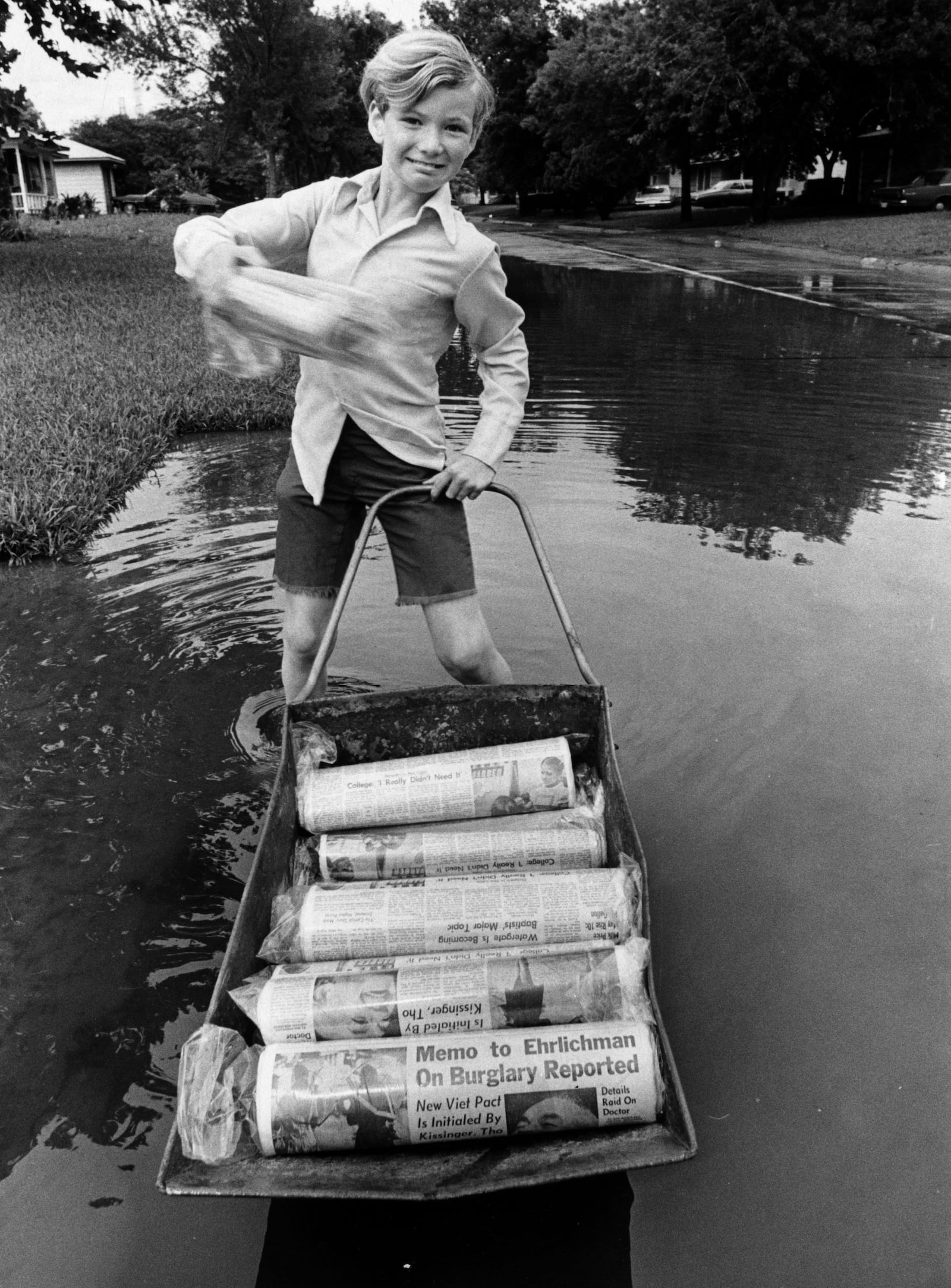 FILE - Gary Magness, 10, Chronicle carrier and a third-grader at Red Bluff Elementary School in Pasadena, delivers his papers on a floating wheelbarrow that skims over high water left by torrential rains. (Greg Smith/Houston Chronicle via AP)
