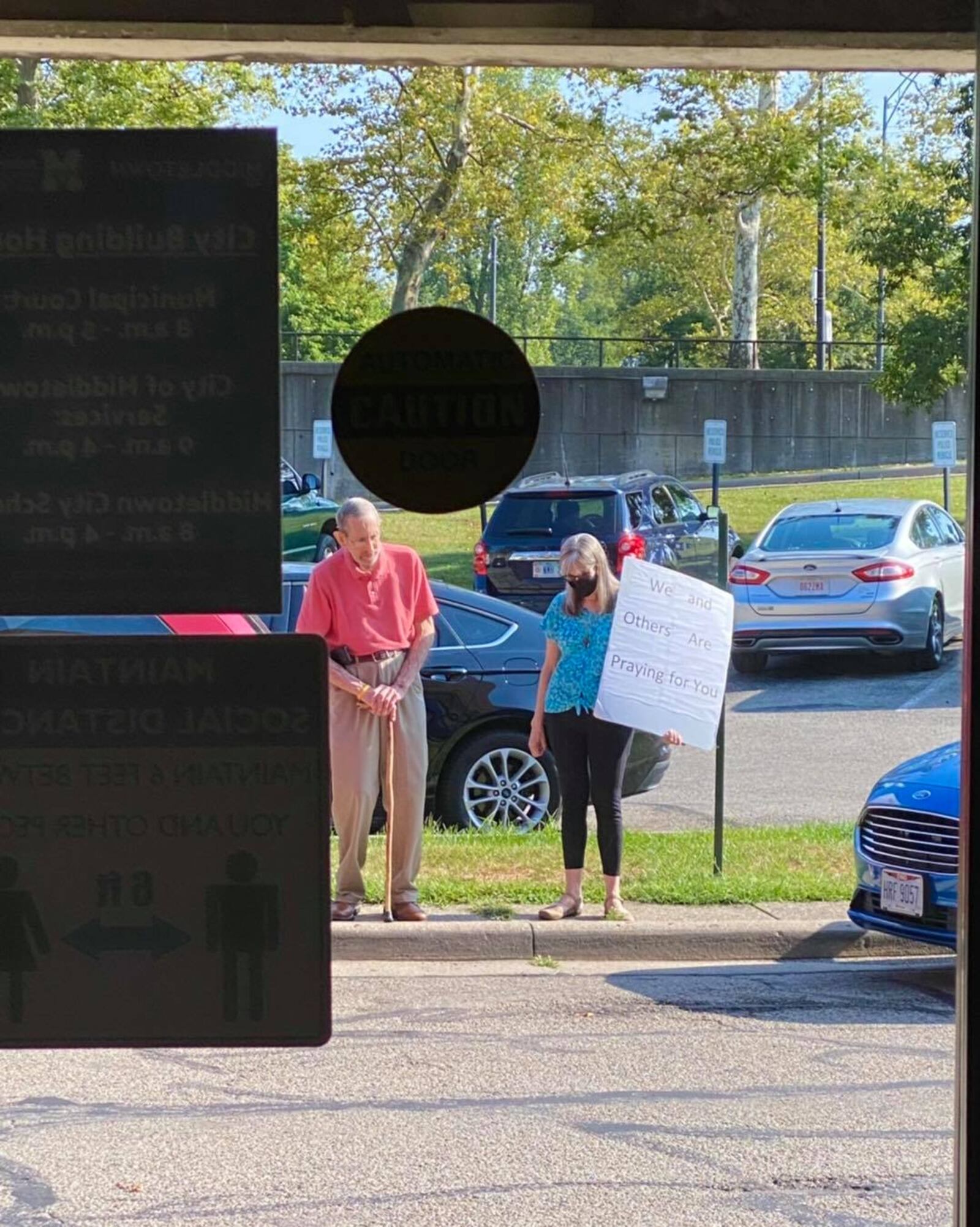 Ray Cary, 81, and Pam Pearson, 75, members of Zion Lutheran Church, stand outside the Middletown police station praying for the officers and their families. Pearson is holding a sign that reads "We and others are praying for you." SUBMITTED PHOTO