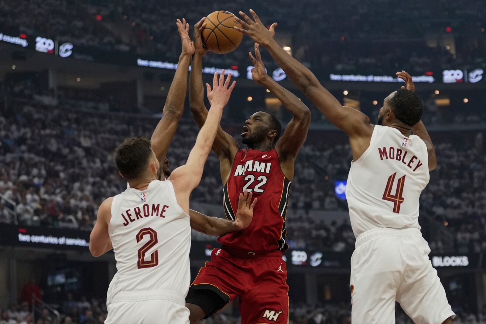 Miami Heat forward Andrew Wiggins (22) shoots between Cleveland Cavaliers forward De'Andre Hunter, behind guard Ty Jerome (2) and Evan Mobley (4) in the first half in Game 1 of an NBA first-round playoff series, Sunday, April 20, 2025, in Cleveland. (AP Photo/Sue Ogrocki)