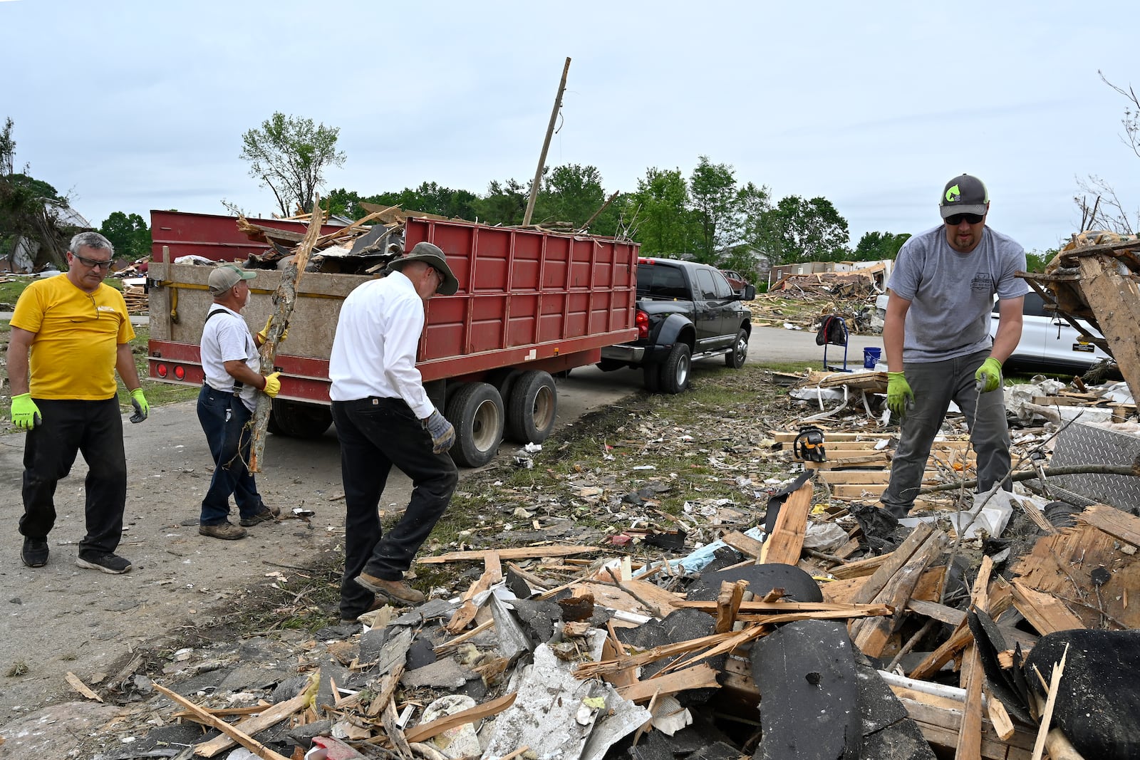 Volunteers load a dump truck with debris during cleanup efforts after severe weather in the Sunshine Hills neighborhood in London, Ky., Monday, May 19, 2025. (AP Photo/Timothy D. Easley)