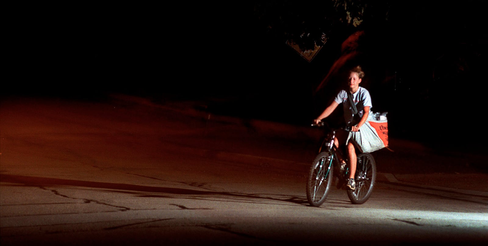 FILE - Christine Bartlett rides her bike between houses as she delivers The Journal Times early Tuesday morning, Aug. 28, 2001, in Racine, Wis. (Gregory Shaver/The Journal Times via AP)