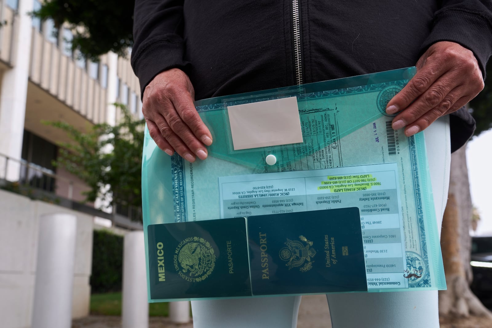 Margarita Velez, mother of Andrea Velez, a U.S. citizen of South L.A, holds to her daughter's current U.S. passport, and her Mexican passport, as she looks for her location, after ICE agents detained Andrea Velez during an immigration raid in downtown, outside the Metropolitan Detention Center in Los Angeles on Wednesday, June 25, 2025. (AP Photo/Damian Dovarganes)